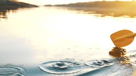 oar paddles on calm water against the background of sunset rays, outdoor activities on a kayak, water sportsの写真素材