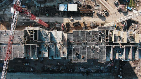 High tower cranes and workers on roof of unfinished building at large construction site on sunny day aerial panoramaの写真素材