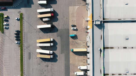 Numerous different trucks stand on parking site near huge warehouse buildings at industrial complex on sunny day upper viewの写真素材