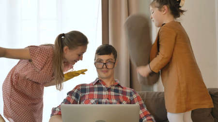 Patient man tries to work online while daughter hits dad face wearing glasses and wife talks in room at quarantine isolationの写真素材