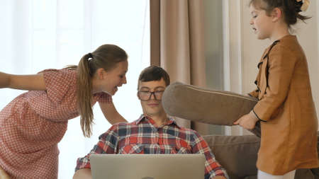 Patient man tries to work online while daughter hits dad face wearing glasses and wife talks in room at quarantine isolationの写真素材