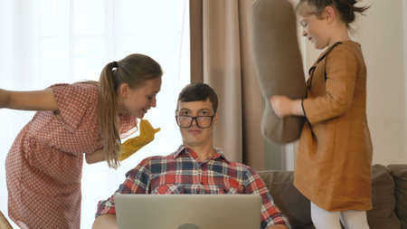 Patient man tries to work online while daughter hits dad face wearing glasses and wife talks in room at quarantine isolationの写真素材