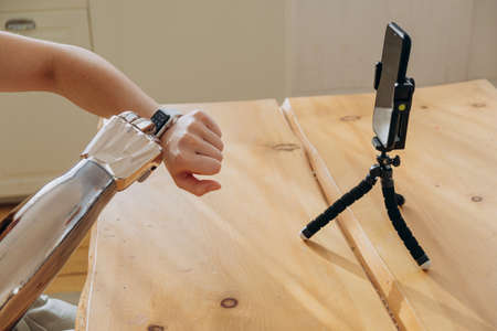 Woman controls bionic arm using smartwatch near phoneの写真素材