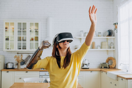 Lady with bionic arm and virtual reality goggles in kitchenの写真素材