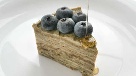 Transparent maple syrup pouring onto piece of flaky cakeの写真素材