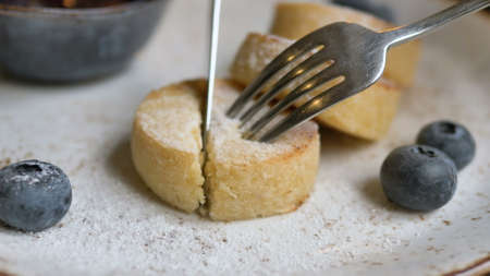 Metal fork and knife cutting cheese pancake piece in cafeの写真素材