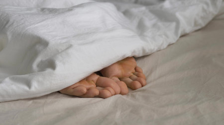 Sleepy person covered with blanket wriggles toes in bedの写真素材