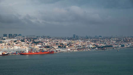 Gigantic ship stands at the pier of the Lisbon seaport and the view of the city from the seaの写真素材