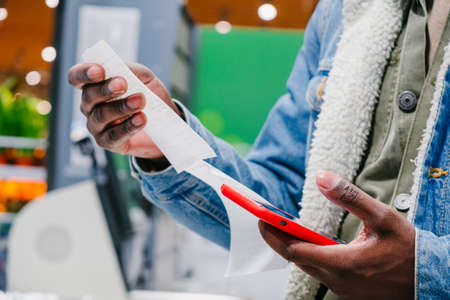 African-American man checks receipt total with smartphoneの写真素材