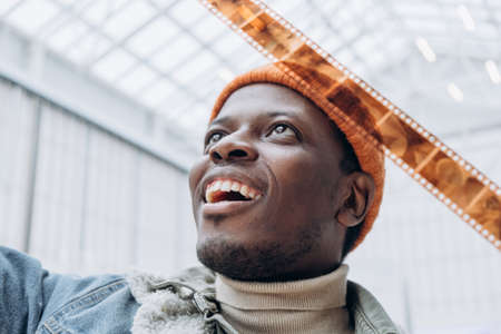 Emotional African-American man looks at vintage film in roomの写真素材