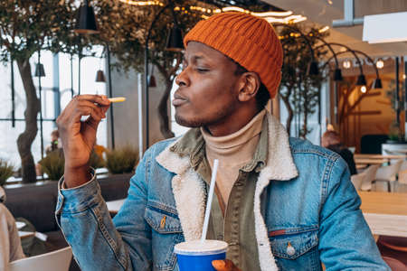 African-America man eats french fries and soda drink in cafeの写真素材