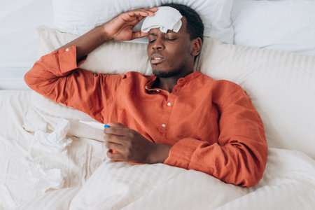 Ill black man with patch checks temperature in large bedの写真素材