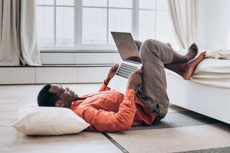 African-American man freelancer works on laptop on floorの写真素材