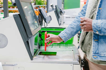 Black guy uses smartphone to pay at self-checkout pointの写真素材
