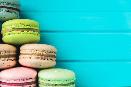 Pyramid of multicolored macaroons on a turquoise wooden background, close up and copy spaceの写真素材