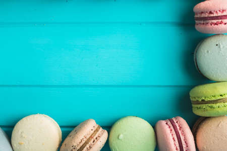 Part of frame of multicolored macaroons or macaron on a turquoise background, almond cookies in the form of decoration, copy space.の写真素材