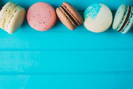 Multicolored fresh macaroon on a turquoise wooden background, almond cookies close-up. Copy spaceの写真素材