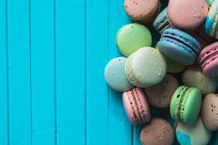 Bunch of multicolored macaroons on a turquoise wooden background, close-up. Copy spaceの写真素材