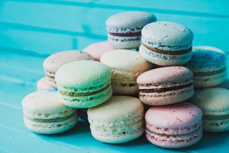 Pyramid of multicolored macaroons on a blue wooden background, french almond cookie, close-up.の写真素材