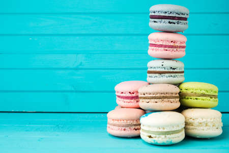 Multicolored macaroons in pastel colors on a blue wooden background, French almond cookies close-up, copy spaceの写真素材
