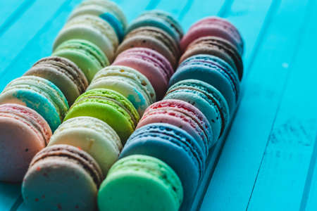 Lines of macaroons in pastel colors lie in a row on a turquoise wooden background, copy spaceの写真素材