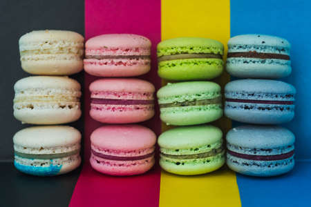 Pyramid of colored macaroons on a multi-colored background close-up, copy spaceの写真素材