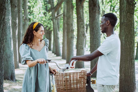Young black man and white woman hold bicycle on alleyの写真素材