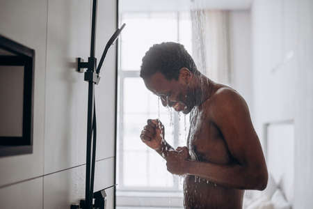 Relaxed African-American man takes shower in bathroomの写真素材