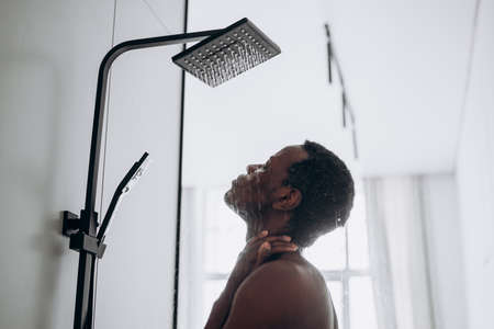 Relaxed African-American man takes shower in bathroomの写真素材