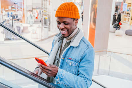 Happy African-American man uses video chat on phone in mallの写真素材