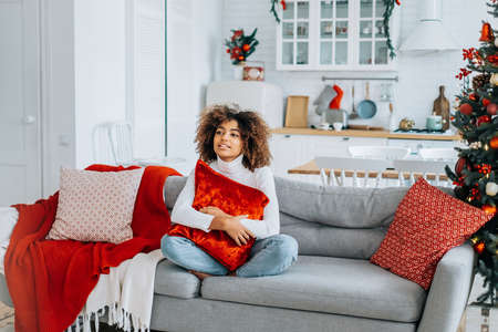Lady holding pillow on head sits in lotus yoga pose on sofaの写真素材