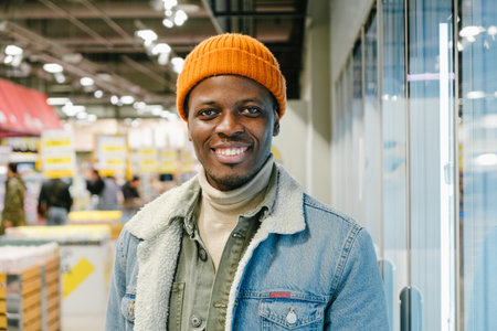 Cheerful African-American guy in denim jacket in supermarketの写真素材