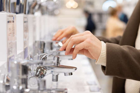 Mens hands choose a water mixer in a construction supermarket, close-up