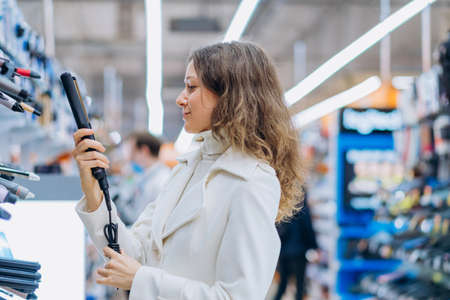 a woman chooses a hair straightener in a home appliance storeの写真素材