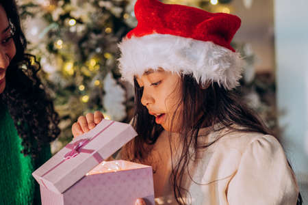 Brunette girl in Christmas hat opens festive presentsの写真素材
