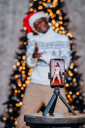 African American man films videos against Chrictmas treeの写真素材