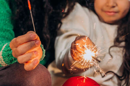 Black mother and daughter in Christmas hats light sparklersの写真素材