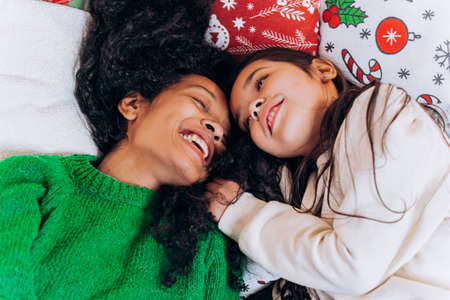 Mother and daughter lie and laugh on Christmas pillowsの写真素材