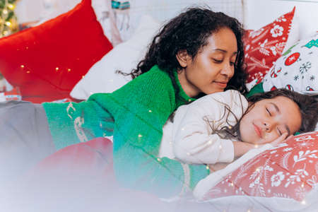 African American mother puts daughter to sleep on Christmasの写真素材