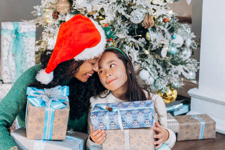 Brunette daughter and black mother open Christmas presentsの写真素材