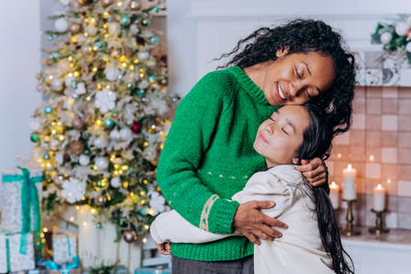 Daughter and African American mum hug tightly and smileの写真素材