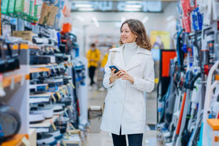 Brunette curly woman chooses equipment for renovationの写真素材