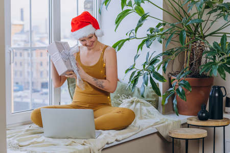 Woman opens Christmas present talking via video callの写真素材