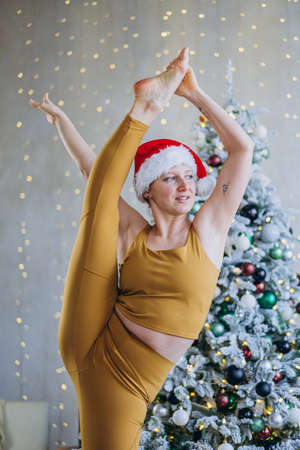 Young woman does split standing against Christmas treeの写真素材