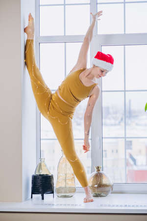Athletic woman does yoga split pose standing on windowsillの写真素材