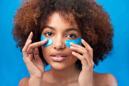 Woman with curly hair poses with blue patches under eyesの写真素材