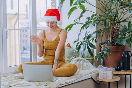 Young woman wrapped in garland talks via videocall by laptopの写真素材