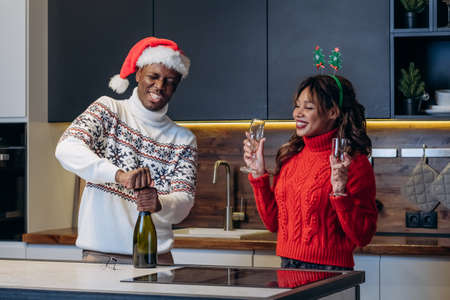 White woman and black man open champagne for Christmasの写真素材