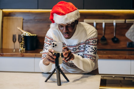 Black man in Santa hat films video in Christmas atmosphereの写真素材
