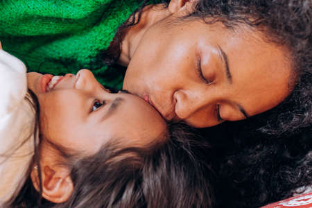 Mother and daughter lie and laugh on Christmas pillowsの写真素材